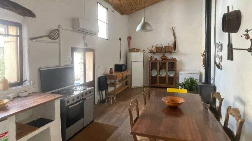 Cocina rústica con mesa de comedor, techo de paja y elementos tradicionales en la casa de pueblo Sencelles