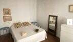Helles Schlafzimmer mit Doppelbett, Holzbalkendecke, Spiegel und Kommode im Stadthaus Sencelles