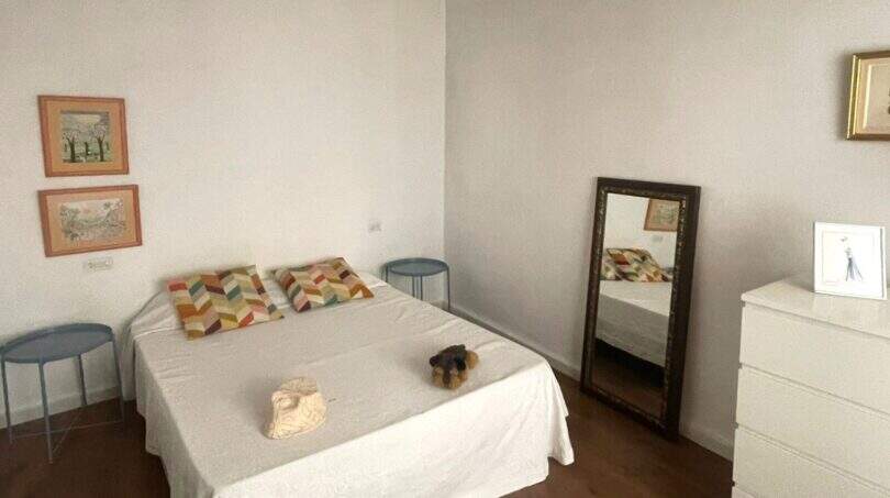 Dormitorio luminoso con cama doble, techo de vigas de madera, espejo y cómoda en la casa de pueblo Sencelles