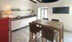 Moderne Küche mit Holzbalken, rotem Retro-Kühlschrank, Kücheninsel und TV im Stadthaus Sencelles