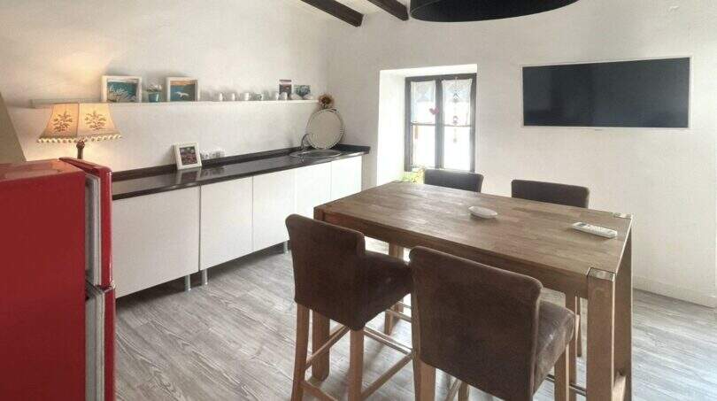 Cocina moderna con vigas de madera, refrigerador retro rojo, isla de cocina y TV en la casa de pueblo Sencelles