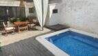 Sonnige Terrasse mit Holzdeck, blauem Mosaikpool und überdachtem Essbereich in Sencelles