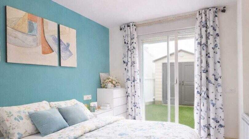 Bright bedroom with turquoise accent wall, double bed and terrace access to the garden, ground floor apartment Palma