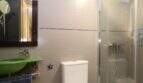 Modern bathroom of the ground floor apartment in Palma with green sink, glass shower and beige wall tiles.