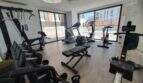 Moderner Fitnessraum mit Geräten und Panoramafenster mit Poolblick im Penthouse Nou Llevant, Palma