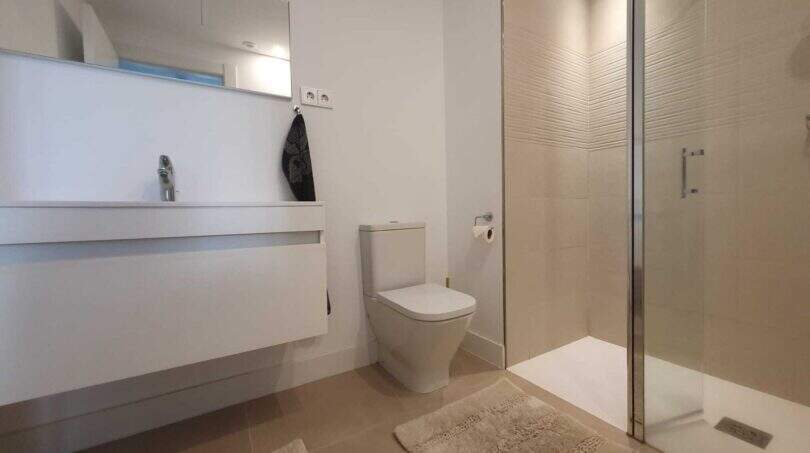 Modernes Badezimmer im Penthouse Nou Llevant mit Dusche, WC und schwebenden Waschtisch in Weiß.