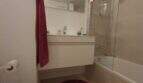 Modernes Badezimmer des Penthouses in Nou Llevant mit Badewanne, Dusche, schwebendem Waschtisch und rotem Akzent-Teppich.