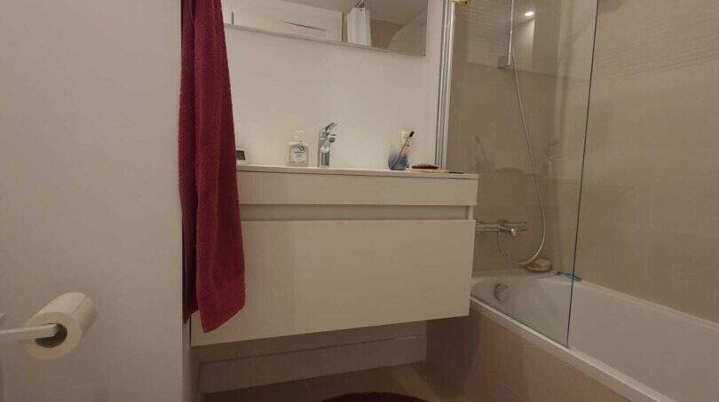 Modernes Badezimmer des Penthouses in Nou Llevant mit Badewanne, Dusche, schwebendem Waschtisch und rotem Akzent-Teppich.