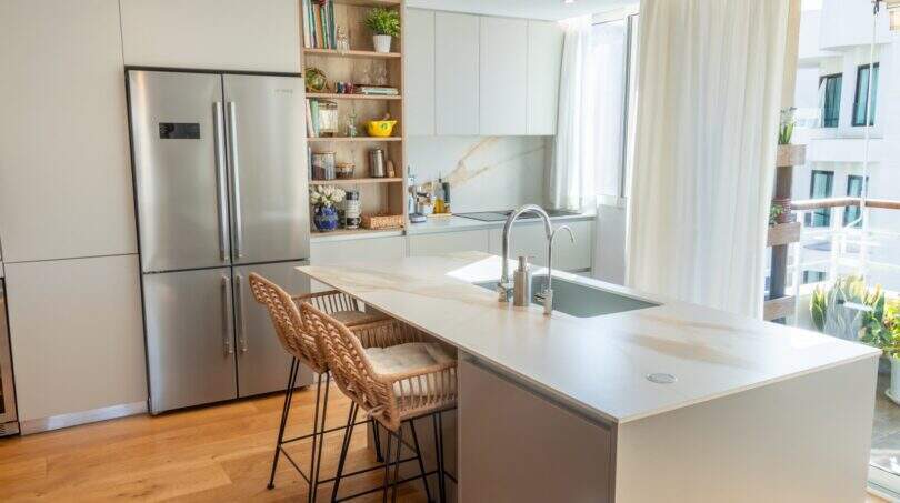 Moderne Designerküche mit Kücheninsel, Marmoroptik-Arbeitsplatte, Edelstahlkühlschrank und Balkonzugang in Palma