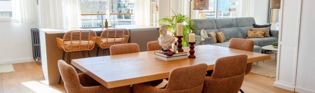 Bright living-dining room with wooden table, rattan chairs and view of Palma's cityscape