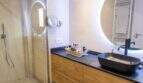 Modernes Badezimmer der Designerwohnung in Palma mit schwarzem Aufsatzbecken, Holzunterschrank und beleuchtetem Rundspiegel.
