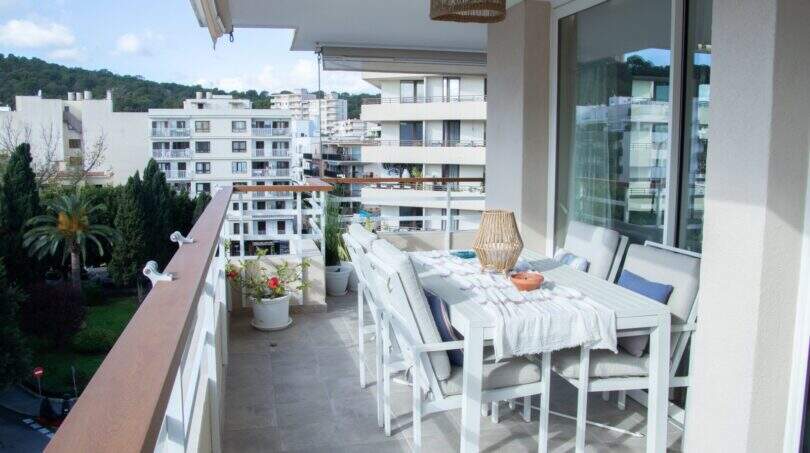Großzügige Dachterrasse mit weißen Gartenmöbeln und Blick auf Palmas Stadtbild und Grünanlagen