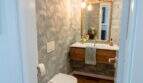 Elegantes Gäste-WC mit Tropenprint-Tapete, vergoldetem Spiegel und Holzwaschtisch in Designerwohnung Palma
