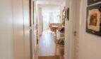 Heller Flur der Designerwohnung in Palma mit Holzboden, weißen Einbauschränken und Blick ins Wohnzimmer