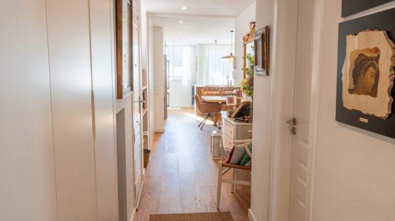 Heller Flur der Designerwohnung in Palma mit Holzboden, weißen Einbauschränken und Blick ins Wohnzimmer