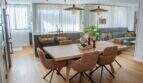 Offener Wohn-Essbereich mit Holztisch, braunen Stühlen, Kücheninsel und grauem Sofa in Designerwohnung Palma
