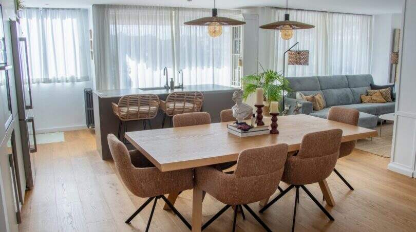 Offener Wohn-Essbereich mit Holztisch, braunen Stühlen, Kücheninsel und grauem Sofa in Designerwohnung Palma