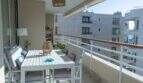 Sonnige Dachterrasse mit weißem Esstisch, Rattanleuchte und Glasgeländer in Designerwohnung am Paseo Maritimo