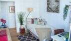 Helles Schlafzimmer mit Einzelbett, bunten Kissen, Stehlampe, Zimmerpflanze und moderner Wandkunst in Palma-Wohnung