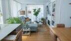 Helles Wohnzimmer mit grauem Sofa, Einbauregal, Parkett und großen Fenstern in Designerwohnung Palma