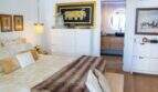 Elegantes Schlafzimmer der Designerwohnung in Palma mit Doppelbett, Pelzdecke, weißen Kommoden und En-suite-Bad.