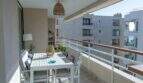 Sonnige Dachterrasse mit weißem Esstisch, Rattanlampe und Meerblick in Designerwohnung am Paseo Maritimo