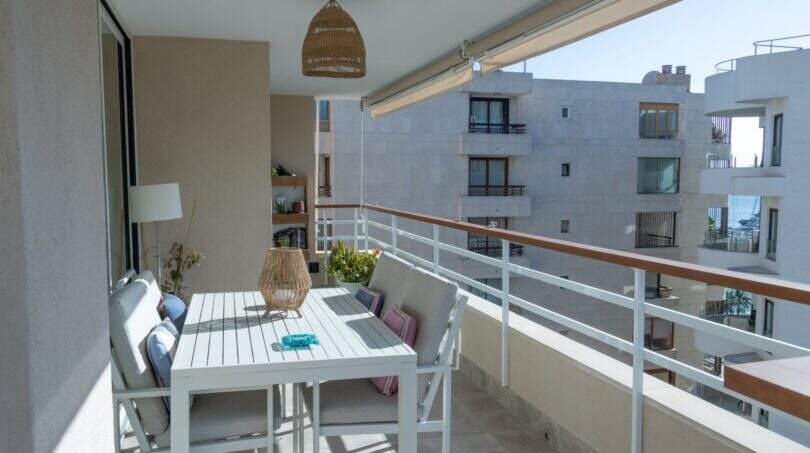 Sonnige Dachterrasse mit weißem Esstisch, Rattanlampe und Meerblick in Designerwohnung am Paseo Maritimo