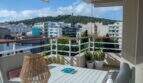Sonnige Dachterrasse mit Stadtblick auf Palma, weißem Tisch, Rattanlampe und Bellver-Burg im Hintergrund