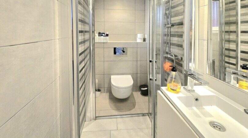 Modern bathroom of the Meereslinie apartment in Palmanova with shower, suspended toilet and light-colored wash basin