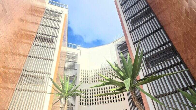 Inner courtyard of the Meereslinie apartment Palmanova with yucca palms and modern building facades under blue sky.