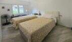 Bright bedroom with two single beds, wooden floor and window to the pool area in Palmanova apartment