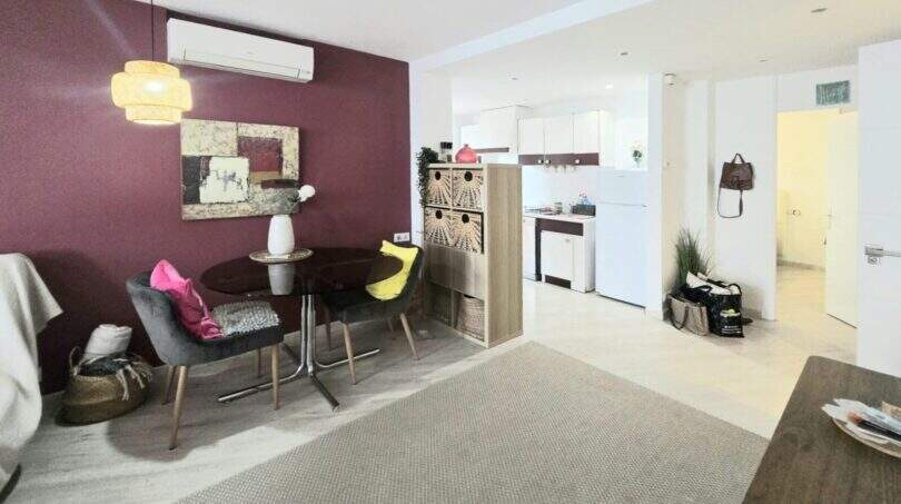 Living area with dining table, air conditioning & open kitchen, bordeaux accent wall, Palmanova