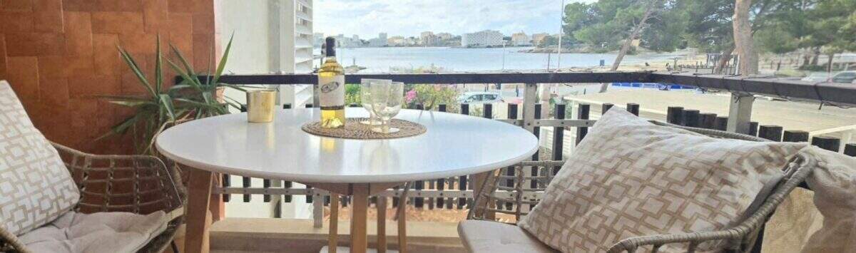 Balcony of the apartment in Palmanova with sea view, rattan chairs and white wine bottle on round table