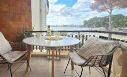 Balkon der Wohnung in Palmanova mit Meerblick, Rattanstühlen und Weißweinflasche auf rundem Tisch