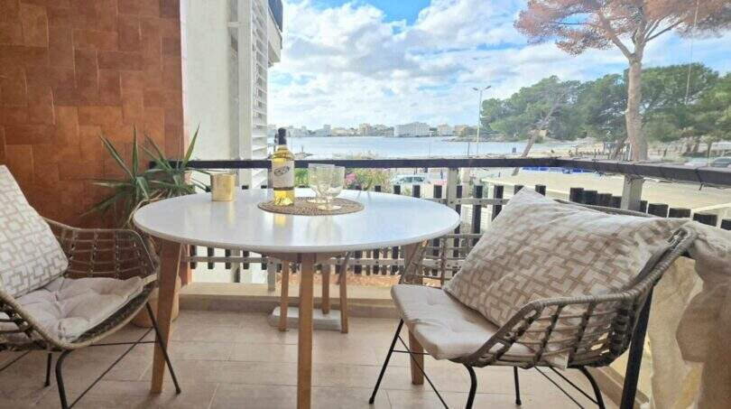 Balcony of the apartment in Palmanova with sea view, rattan chairs and white wine bottle on round table