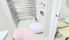 Modern bathroom of the Meereslinie apartment in Palmanova with shower, wall-mounted toilet and pink bath mat