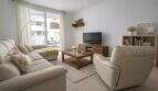 Helles Wohnzimmer mit Ecksofa, Holzmöbeln und Balkonzugang in modernem Apartment in Palma de Mallorca