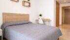 Helles Schlafzimmer mit Doppelbett, Holzregalen und Schreibtisch in modernem Apartment in Palma de Mallorca