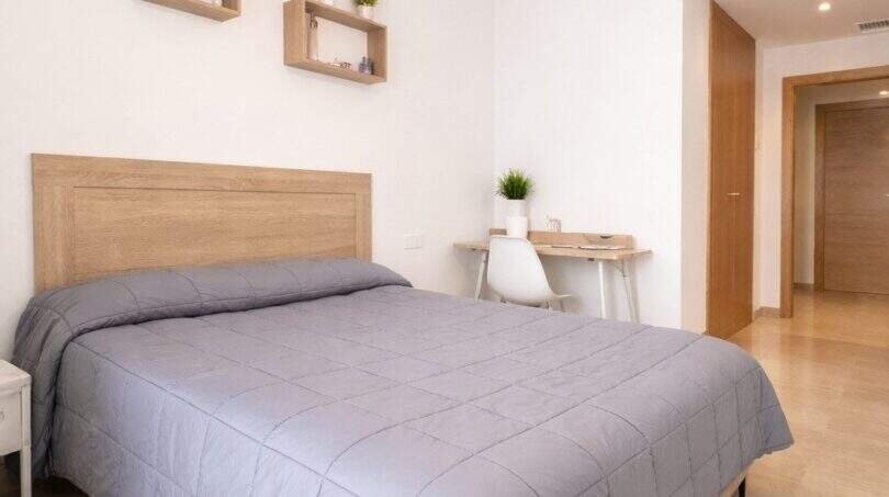Helles Schlafzimmer mit Doppelbett, Holzregalen und Schreibtisch in modernem Apartment in Palma de Mallorca