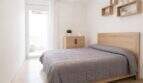 Helles Schlafzimmer mit Doppelbett, Holzmöbeln, Wandregalen und Zugang zum Balkon in Palma