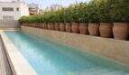 Eleganter Dachpool mit Natursteinverkleidung und Terrakotta-Pflanzkübeln auf urbanem Rooftop in Palma