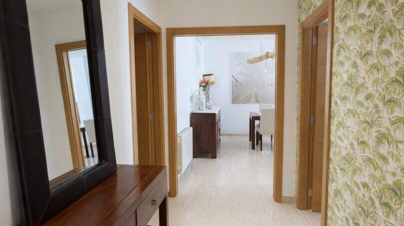 Eleganter Flur mit Tropenblatt-Tapete, Holzkonsole, Spiegel und Blick ins Esszimmer in Palma-Villa