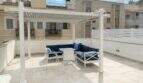Soleada terraza en la azotea con pérgola blanca, mobiliario lounge azul y vistas a la ciudad en Palma de Mallorca