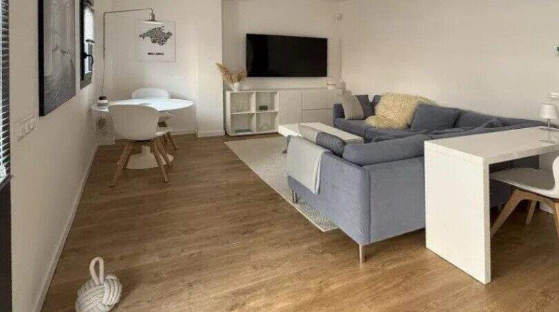 Helles Wohnzimmer mit grauem Sofa, TV-Bereich und Essplatz, Parkettboden, modernes Design im Penthouse Palma