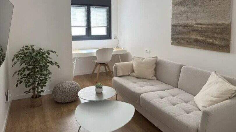 Helles Wohnzimmer des Penthouses in Palma mit Sofa, Holzboden, Schreibtischbereich und modernem Dekor.