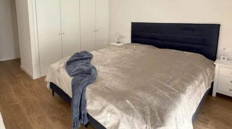 Helles Schlafzimmer im Penthouse Palma mit Doppelbett, schwarzem Polsterkopfteil und weißem Einbauschrank