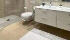 Modernes Badezimmer des Penthouses in Palma mit begehbarer Dusche, Doppelwaschbecken und eleganten Beige-Tönen.