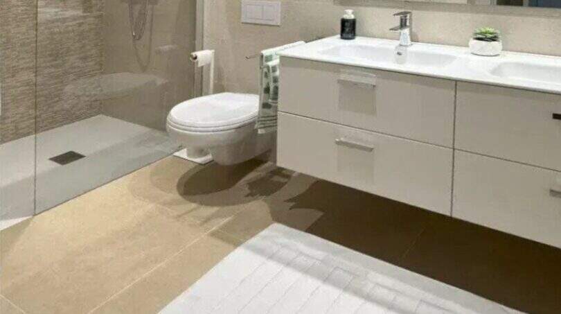 Modernes Badezimmer des Penthouses in Palma mit begehbarer Dusche, Doppelwaschbecken und eleganten Beige-Tönen.