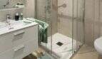 Modernes Badezimmer des Penthouses mit Glasdusche, weißem Waschtisch und mintgrünen Akzenten in Palma