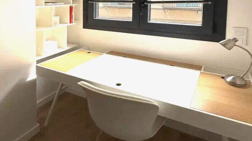 Helles Arbeitszimmer mit weißem Schreibtisch, Stuhl, Wandregal und Fenster mit Jalousien im Penthouse Palma